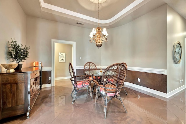 tiled dining room featuring visible vents, ornamental molding, baseboards, a tray ceiling, and a notable chandelier