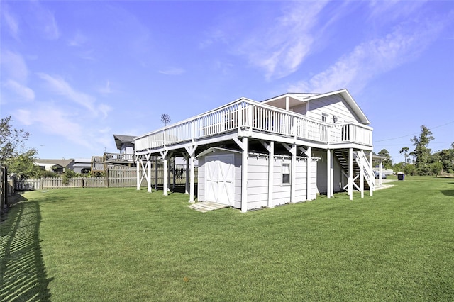 back of house featuring stairs, a wooden deck, a shed, fence, and a yard