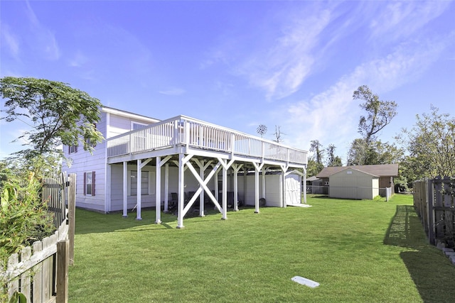 rear view of house featuring a deck, fence, a yard, and a storage shed
