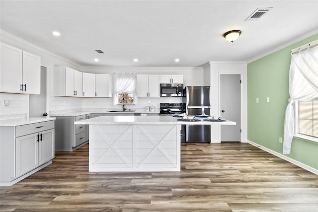 kitchen with decorative backsplash, appliances with stainless steel finishes, a sink, visible vents, and crown molding