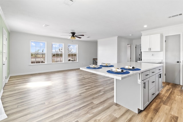 kitchen featuring visible vents, crown molding, light wood finished floors, and light countertops
