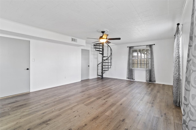 unfurnished living room with wood finished floors, stairs, ceiling fan, baseboards, and visible vents