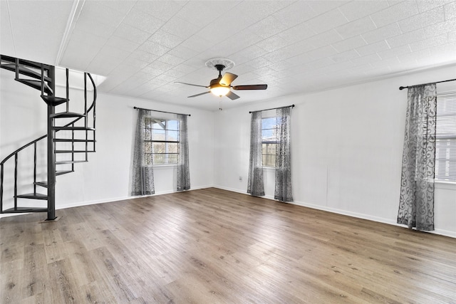 unfurnished living room with baseboards, wood finished floors, a ceiling fan, and stairs