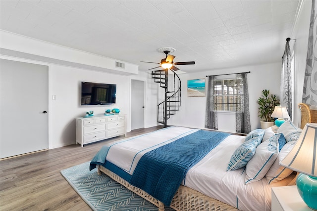 bedroom with wood finished floors, visible vents, and ceiling fan