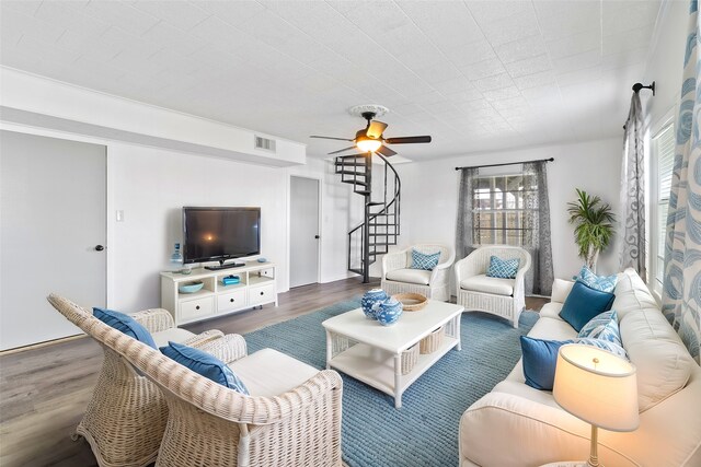 living area with visible vents, wood finished floors, ceiling fan, and stairway