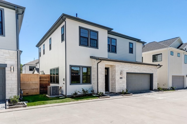 view of front of property with central air condition unit, a garage, stone siding, concrete driveway, and fence