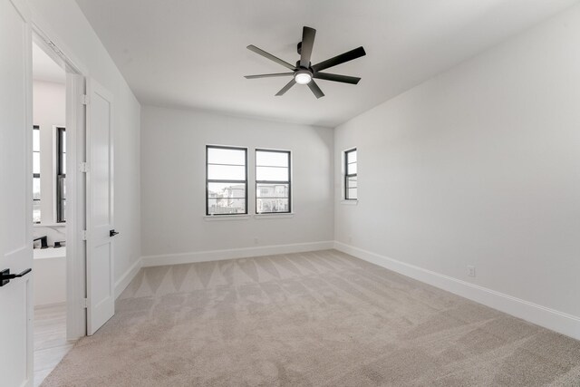 unfurnished room with ceiling fan, baseboards, and light carpet