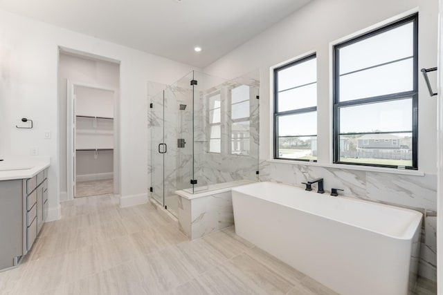 full bath featuring recessed lighting, vanity, a soaking tub, a spacious closet, and a marble finish shower