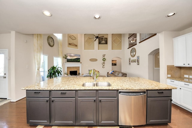 kitchen featuring a ceiling fan, arched walkways, dishwasher, a sink, and open floor plan