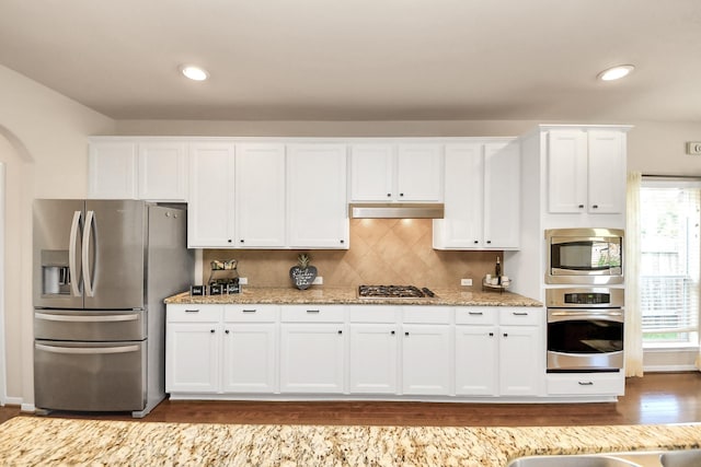 kitchen with under cabinet range hood, white cabinetry, appliances with stainless steel finishes, and dark wood-style floors