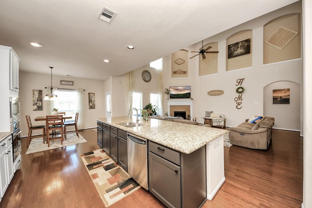 kitchen with ceiling fan, stainless steel dishwasher, a fireplace, a sink, and open floor plan