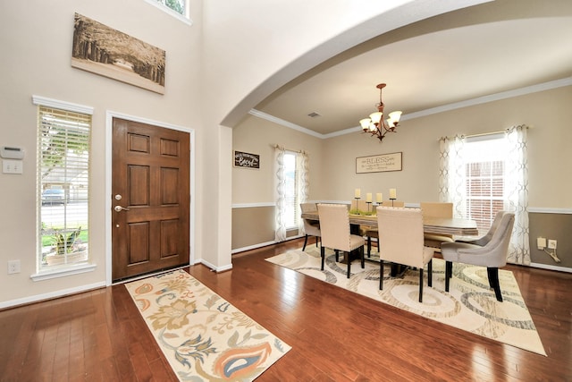foyer with ornamental molding, baseboards, a chandelier, hardwood / wood-style flooring, and arched walkways