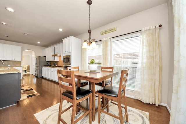 dining area featuring recessed lighting, arched walkways, and dark wood finished floors