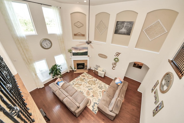 living room featuring a towering ceiling, a healthy amount of sunlight, and a fireplace