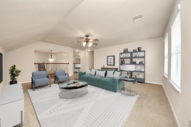 carpeted living room featuring ceiling fan, visible vents, baseboards, and vaulted ceiling