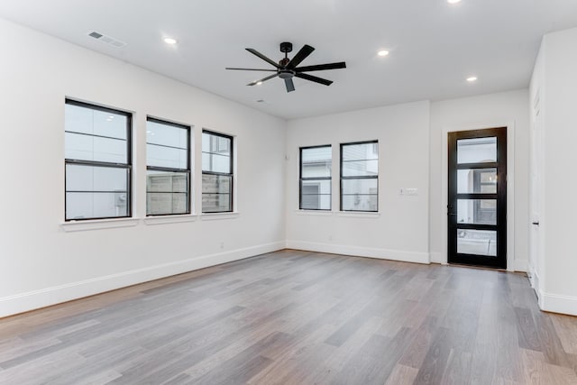 unfurnished room featuring a ceiling fan, a wealth of natural light, wood finished floors, and baseboards