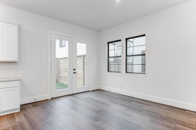 doorway with baseboards, french doors, and light wood-type flooring