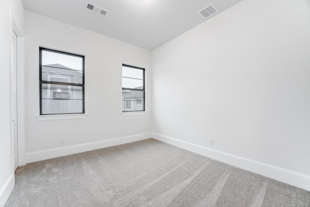 empty room with baseboards, visible vents, and carpet
