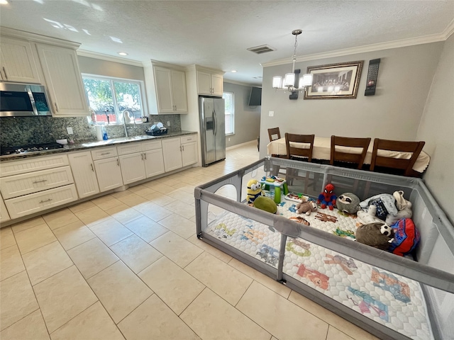 13505 Orleans St, Houston, TX 77015 - kitchen with appliances with stainless steel finishes, tasteful backsplash, crown molding, light tile patterned floors, and a chandelier