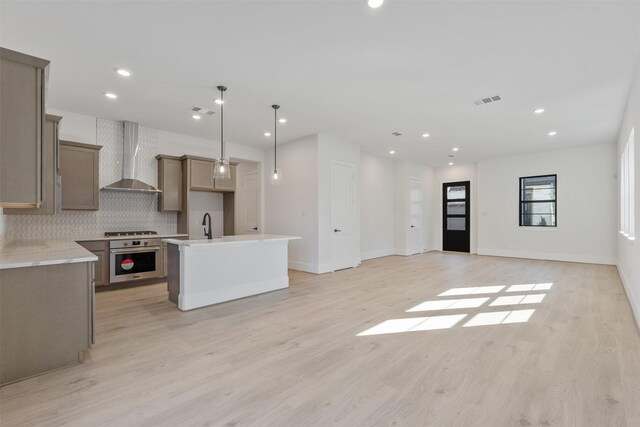 kitchen with recessed lighting, stainless steel appliances, decorative backsplash, wall chimney range hood, and open floor plan