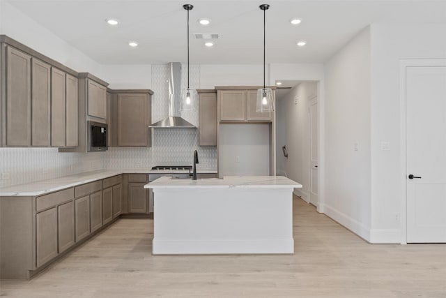 kitchen featuring wall chimney exhaust hood, visible vents, light wood-style floors, and tasteful backsplash