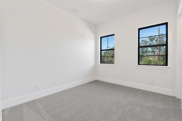 carpeted empty room featuring baseboards and visible vents