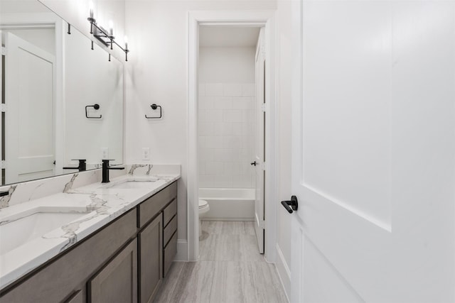 bathroom featuring toilet, double vanity, and a sink