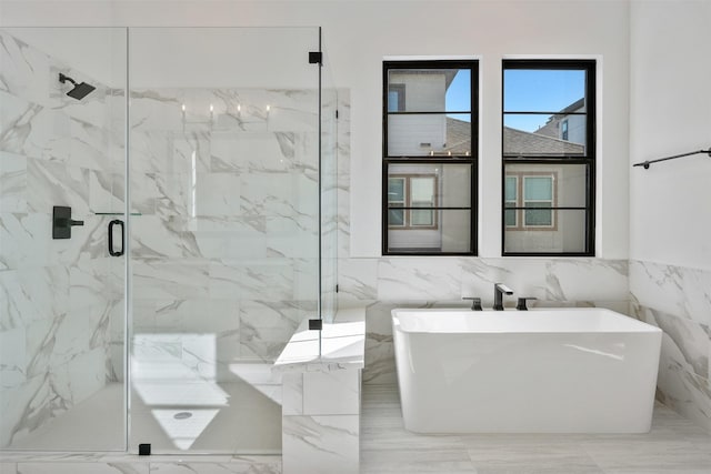 bathroom featuring tile walls, a freestanding bath, a marble finish shower, and marble finish floor