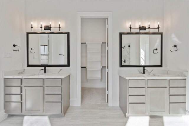 full bath featuring two vanities, baseboards, and a sink