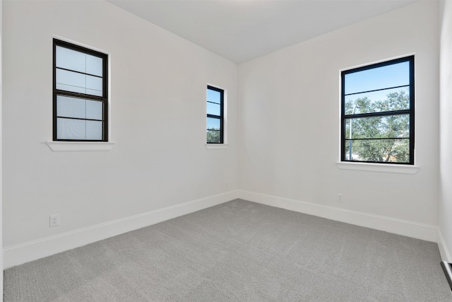carpeted spare room with plenty of natural light and baseboards