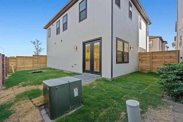 back of house featuring french doors, a fenced backyard, and a yard