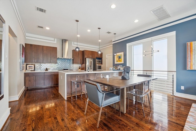 1946 Vermont St, Houston, TX 77019 - kitchen featuring wall chimney exhaust hood, stainless steel appliances, dark wood finished floors, light countertops, and backsplash