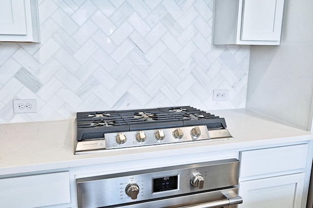 interior details with tasteful backsplash, stainless steel gas stovetop, wall oven, light countertops, and white cabinetry