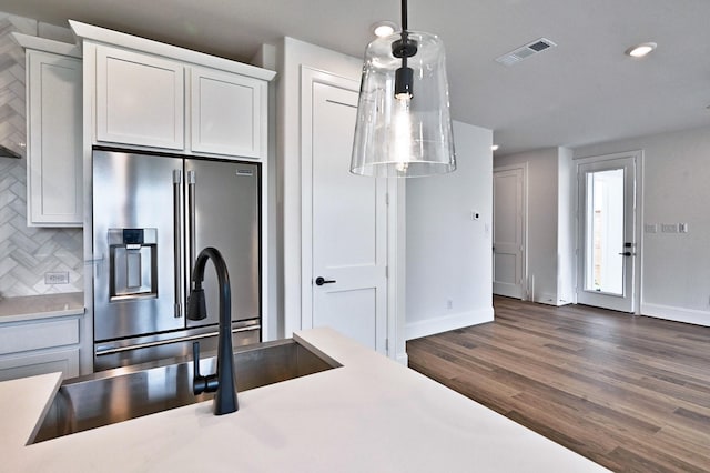 kitchen featuring tasteful backsplash, wood finished floors, stainless steel fridge, light countertops, and visible vents
