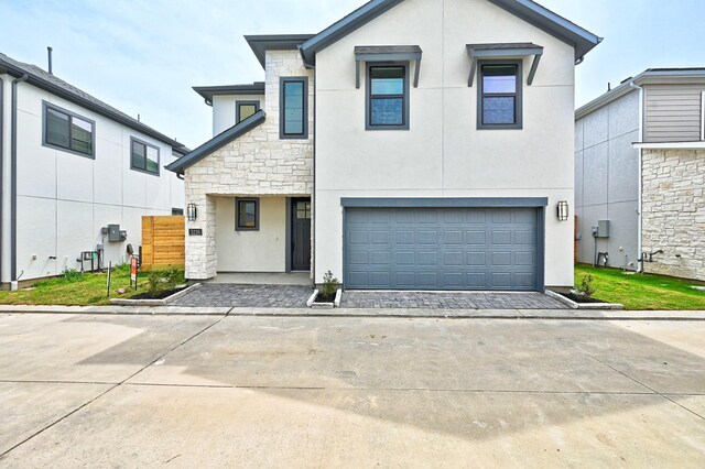 traditional-style house with stucco siding, driveway, an attached garage, and stone siding