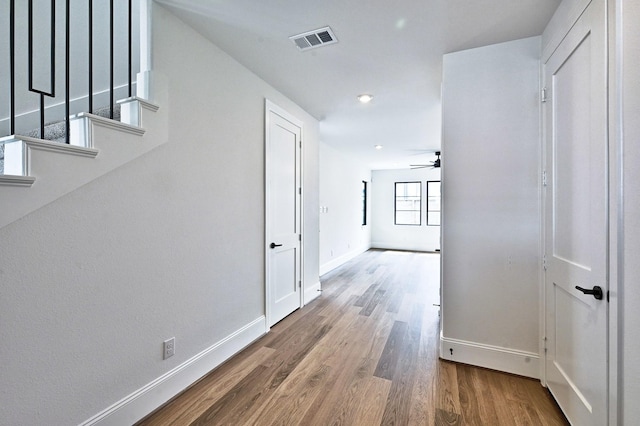 hall featuring baseboards, visible vents, and wood finished floors