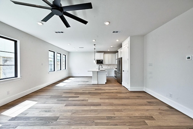 unfurnished living room featuring visible vents, recessed lighting, and baseboards