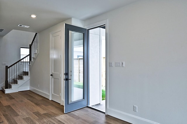 entrance foyer with stairs, visible vents, wood finished floors, and baseboards