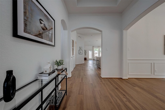 hall with wood finished floors and arched walkways