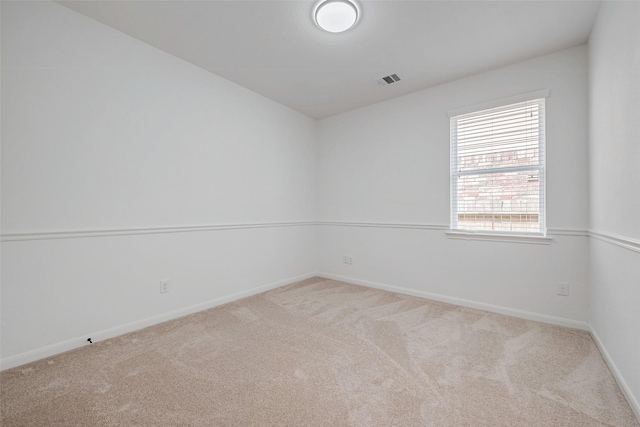 empty room with carpet, visible vents, and baseboards