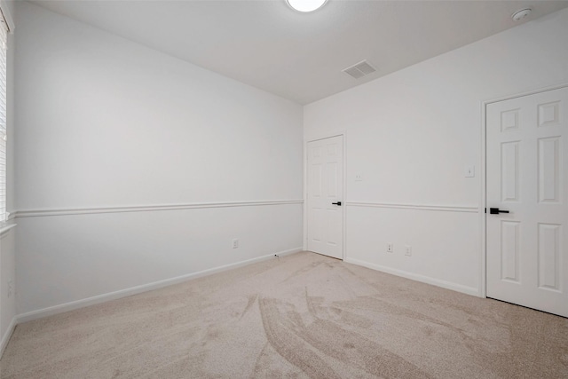 carpeted spare room featuring baseboards and visible vents