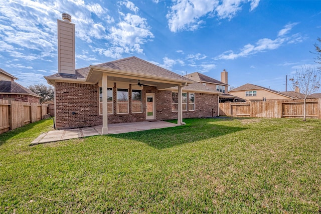 back of property with a lawn, a patio, ceiling fan, and a chimney
