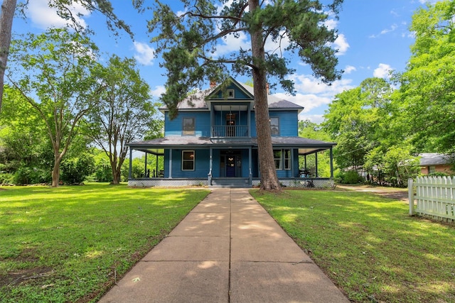victorian home featuring covered porch, fence, and a front lawn