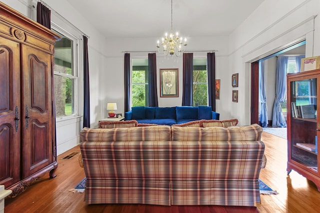 living area featuring an inviting chandelier, a wealth of natural light, wood finished floors, and visible vents