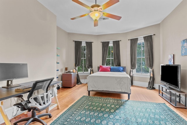 bedroom with wood finished floors, ceiling fan, visible vents, and baseboards