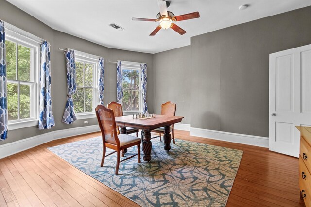 dining space with baseboards, visible vents, wood finished floors, and ceiling fan