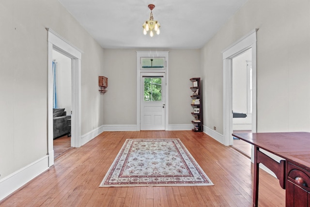 entrance foyer featuring an inviting chandelier, light wood-style floors, and baseboards