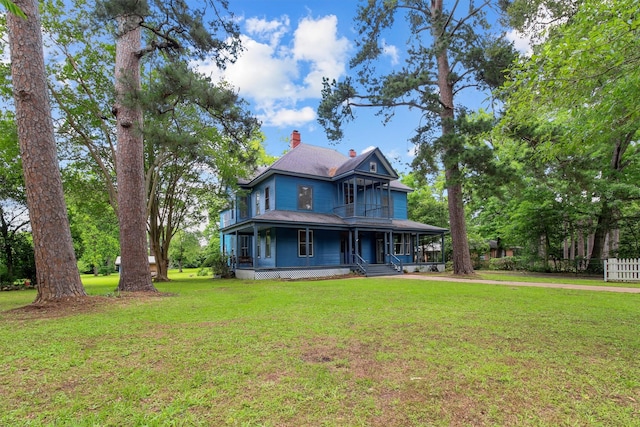 view of front of home with a chimney, a porch, and a front lawn
