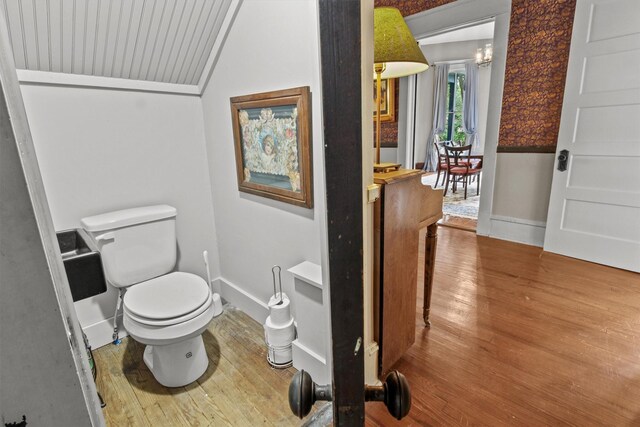 bathroom featuring baseboards, wood finished floors, and toilet