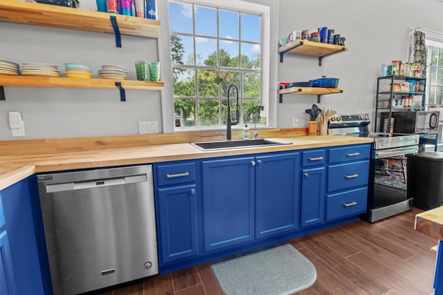 kitchen featuring butcher block countertops, a sink, stainless steel appliances, open shelves, and blue cabinetry